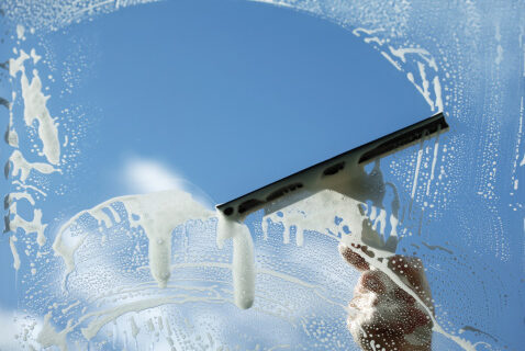 Commercial Window Squeegee Cleaning Squeegee gliding across a soapy office window during commercial window cleaning