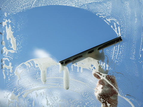 Commercial Window Squeegee Cleaning Squeegee gliding across a soapy office window during commercial window cleaning