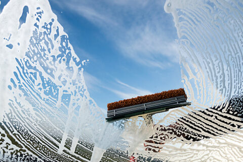 Window Cleaning Squeegee Squeegee removing soap suds from a window during professional window cleaning
